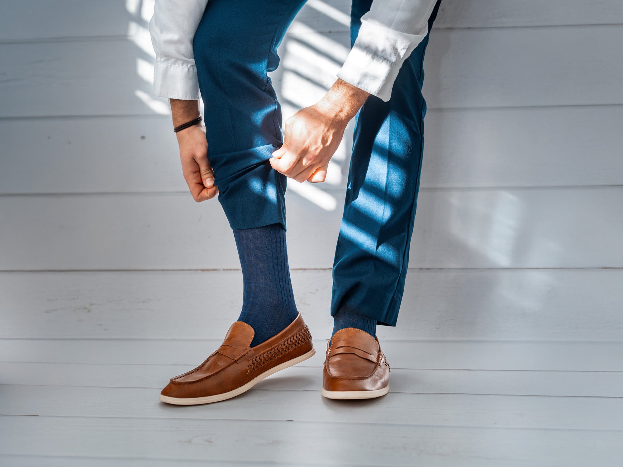 Mann trägt blaue Businesssocken von BLACKSOCKS zu braunen Loafers und blauer Hose.